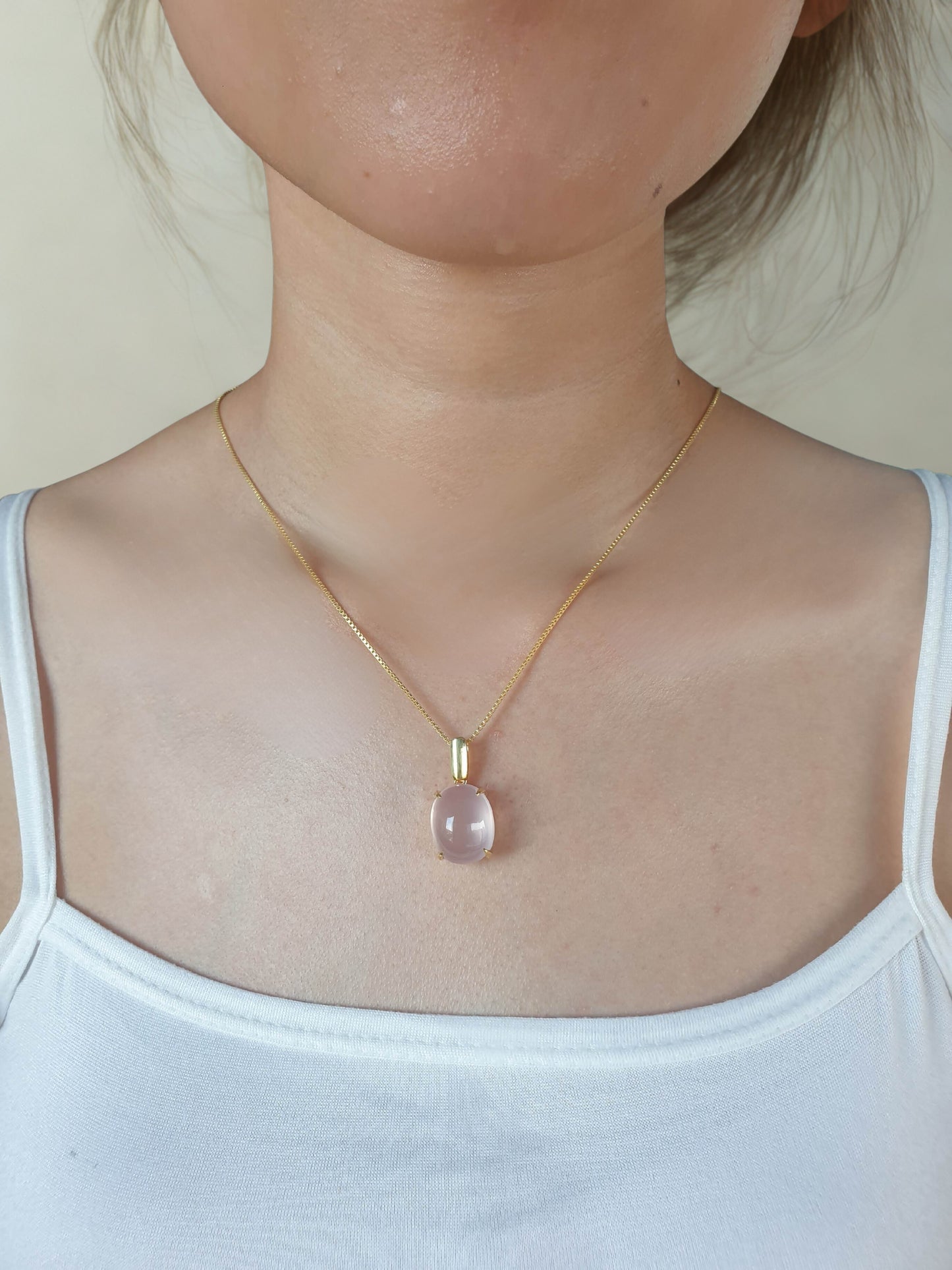 Necklace with a pink pendant worn by a person in a white tank top.